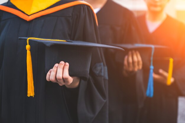 Perto de graduados segurando chapéus nas mãos