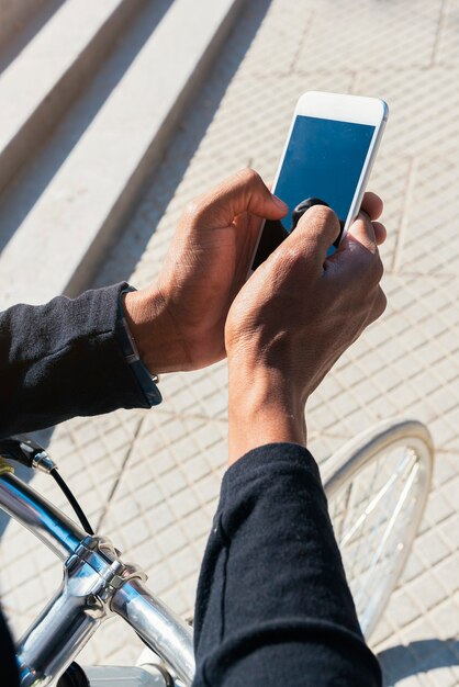 Perto de jovem usando telefone celular e bicicleta de engrenagem fixa na rua.