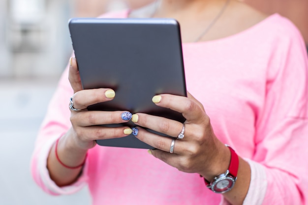 Perto de mãos femininas com tablet na rua de verão