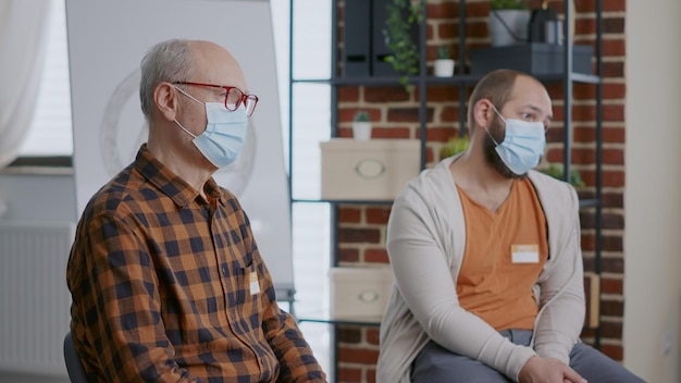 Perto de pacientes com dependência usando máscara facial em uma reunião de grupo, ouvindo os conselhos do terapeuta. pessoas participando do programa de sessão de terapia durante a pandemia de coronavírus.