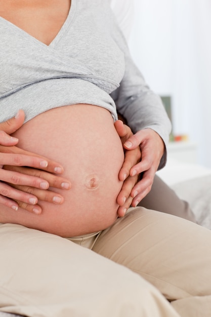 Perto de pais futuros que sentem o bebê sentado na cama