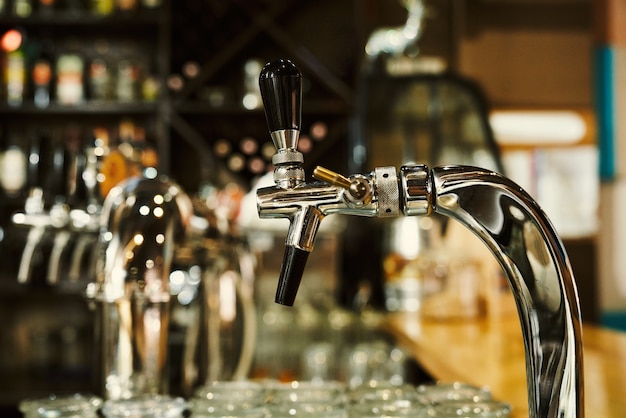 Perto de torneiras de cerveja metálicas no balcão do bar. Conceito de bar moderno, equipamento de cervejaria.