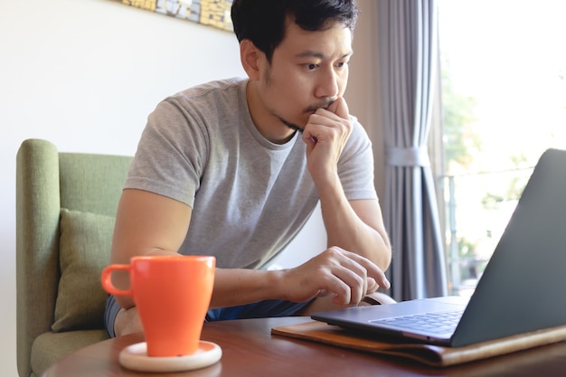 Perto de um homem sério asiático, trabalhando em seu laptop no café.