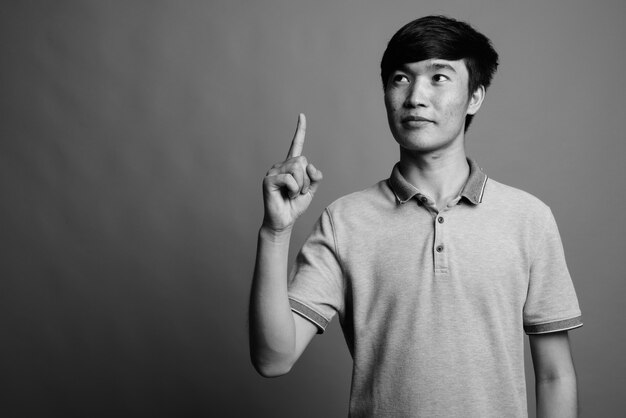 Perto de um jovem asiático vestindo uma camisa pólo cinza