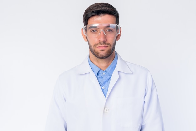 Perto de um jovem médico persa barbudo bonito com óculos de proteção isolados
