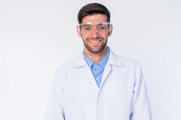 Perto de um jovem médico persa barbudo bonito com óculos de proteção isolados