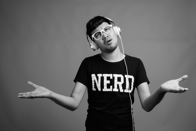 Perto de um jovem nerd asiático usando óculos enquanto ouve música