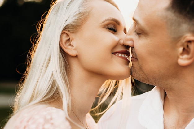 Perto de um lindo jovem casal sorrindo antes do beijo. amando husbad e esposa beijando otudoor enquanto namorava contra o pôr do sol.