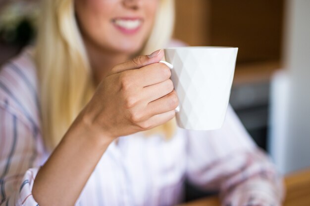 Perto de uma jovem loira tomando café em casa