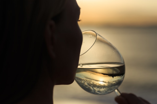 Foto perto de uma jovem mulher bonita bebendo vinho branco