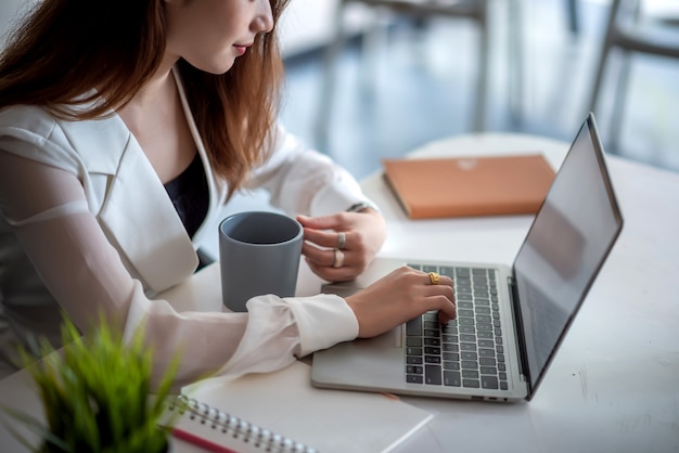 Perto de uma jovem trabalhando em um laptop na mesa do escritório