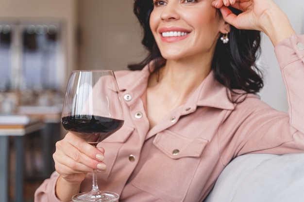 Foto perto de uma moça bonita e alegre tomando uma bebida alcoólica em um restaurante