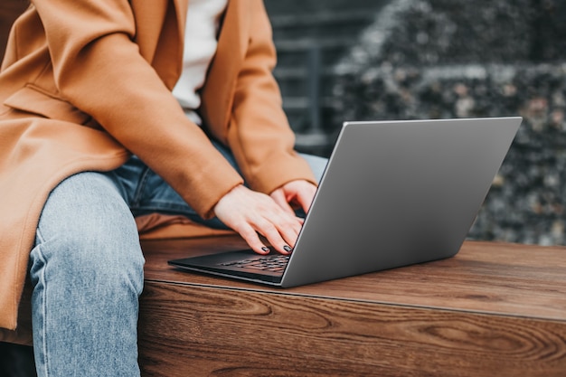 Perto de uma mulher com as mãos digitando em um laptop na rua contra um prédio de escritórios. Distância de trabalho de empresária. Fechar-se