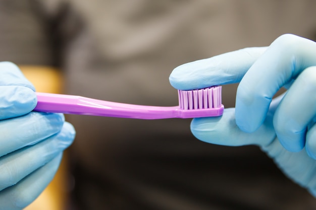 Perto de uma mulher dentista ou estomatologista segurando e mostrando a escova de dentes roxa, demonstra rigidez das cerdas. Higiene dos dentes.
