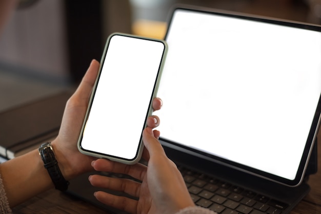 Perto de uma mulher segurando um telefone celular com uma tela em branco