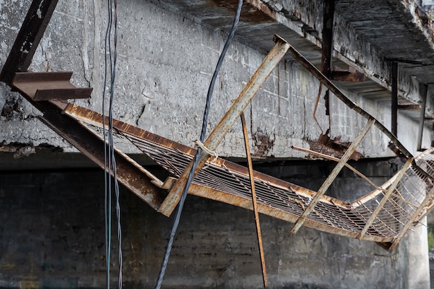 Foto perto de uma passarela de metal quebrada em uma velha ponte de concreto armado.