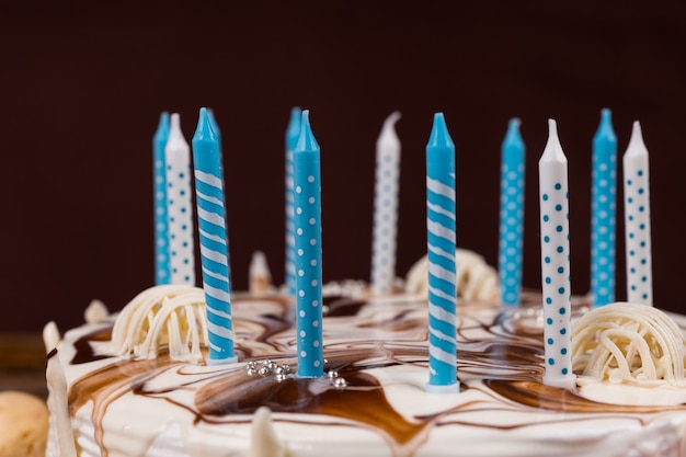 Foto perto de velas de aniversário em um bolo caseiro branco, na mesa de madeira