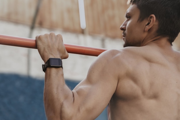 Perto do atleta praticando ginástica com smartwatch no pulso.