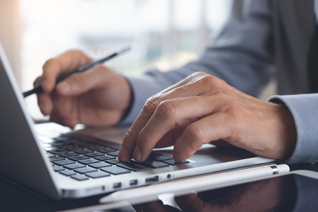 Perto do empresário trabalhando em um laptop na mesa do escritório