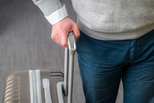 Perto do homem de negócios jovem com bagagem mala no tapete no aeroporto.