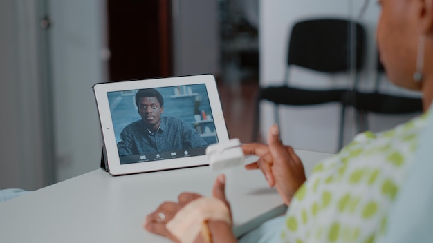 Perto do paciente usando videochamada no tablet digital para falar com o homem enquanto estava deitado na cama da enfermaria do hospital. Pessoa falando com um amigo em videoconferência online no dispositivo. Comunicação remota