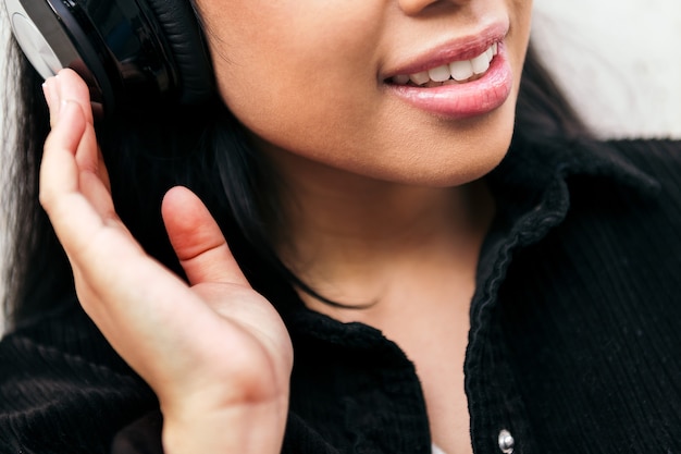 Perto do sorriso de uma jovem alegre com fones de ouvido, curtindo ouvir música