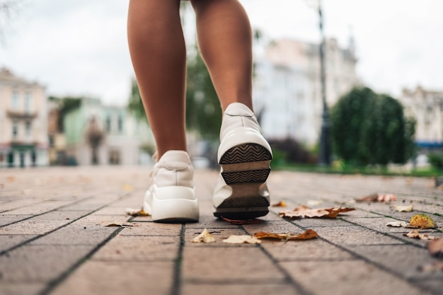 Perto dos pés de um corredor correndo com folhas de outono, treinando para uma maratona fitness, estilo de vida saudável