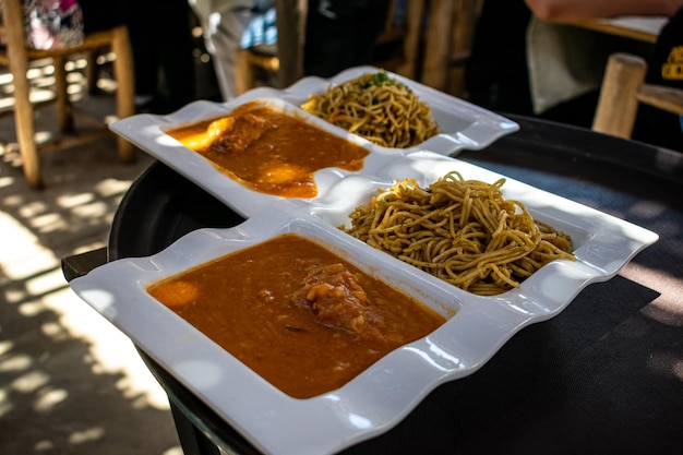 Peruanisches Essen SOPA SECA CON CARAPULCRA, traditionelle Gerichte in doppelten weißen Tellern.