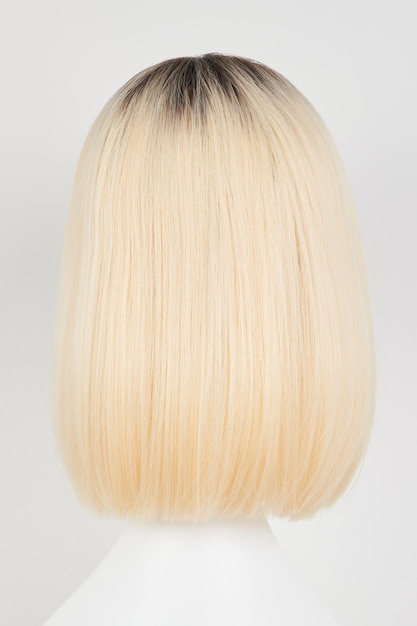 Peruca loira de aparência natural em cabeça de manequim branca corte de cabelo de comprimento médio no suporte de peruca de plástico isolado em fundo branco vista traseira