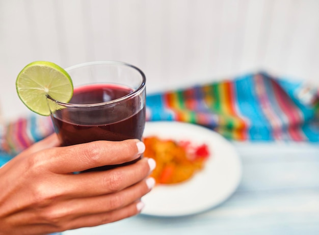 Peruvian PURPLE CORN DRINK Chicha morada púrpura dulce tradicional peruana bebida de maíz Mujer sosteniendo un vaso con típico jugo fresco peruano chicha morada enfoque selectivo