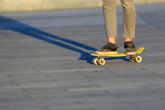 Pés adolescente andando de skate na cidade