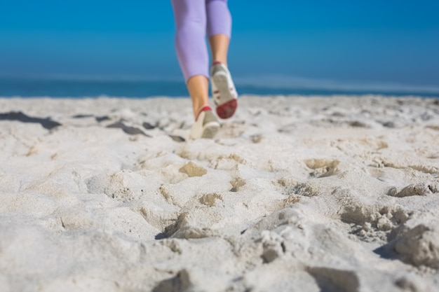 Pés da mulher desportivos jogando na areia