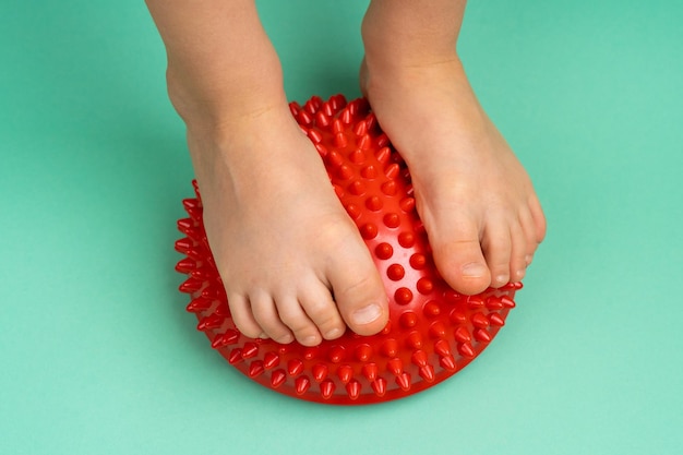 Pés das crianças com um balanceador vermelho sobre fundo verde claro tratamento e prevenção de pés chatos
