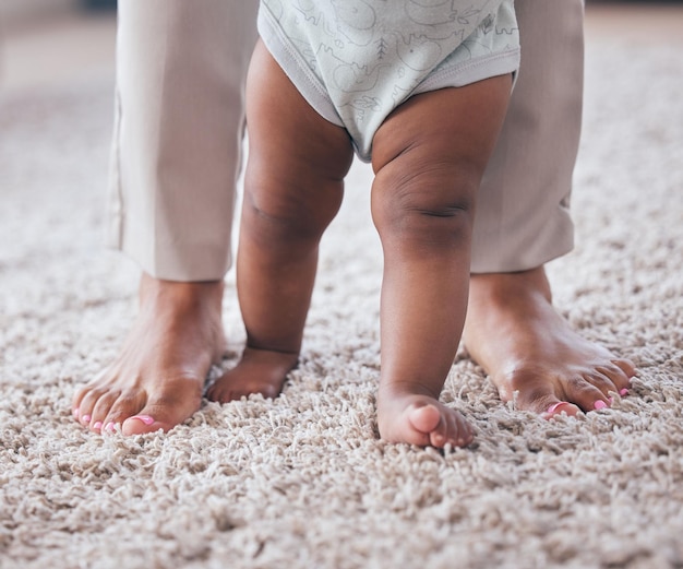 Foto pés de bebê aprendendo a andar com a mãe na sala de estar com desenvolvimento de mobilidade