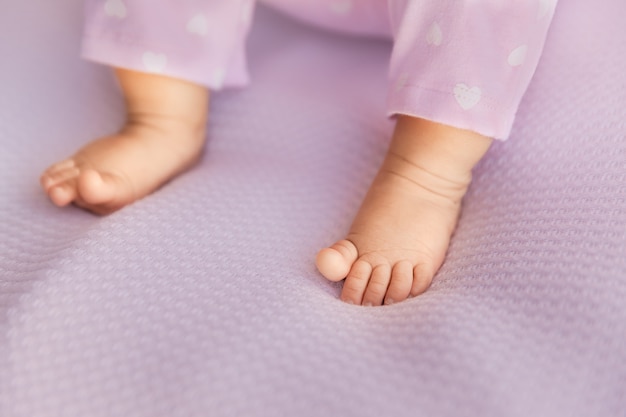 Foto pés de bebê menina em tecido lilás, dedos minúsculos em um foco seletivo