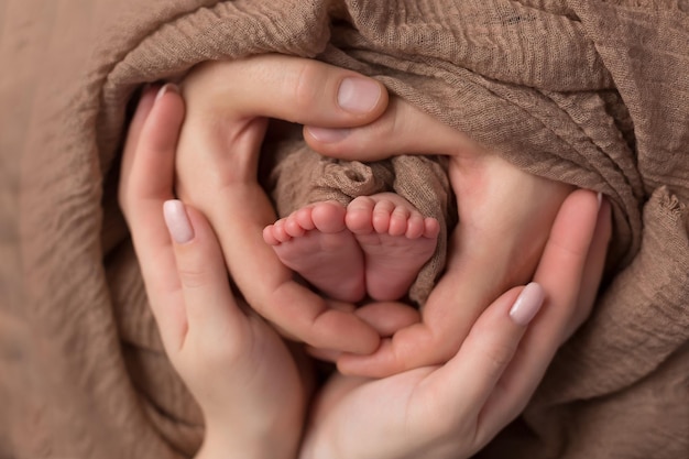 Pés de bebê nas mãos da mãe. Pernas de um pequeno recém-nascido em close-up de braços. Família e criança. pai feliz