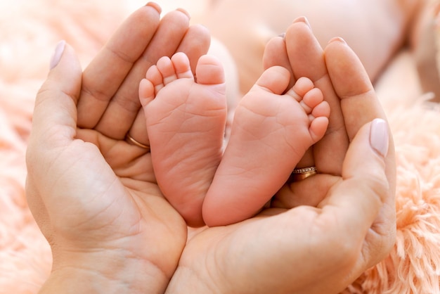 Pés de bebê nas mãos da mãe Pés minúsculos bebê recém-nascido em forma de mão feminina