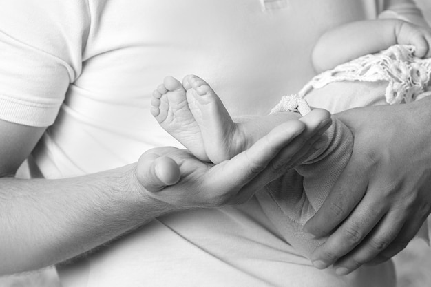 Foto pés de bebê nas mãos do pai pequenos pés de bebê recém-nascido nas mãos masculinas closeup pai e seu filho conceito de família feliz foto em preto e branco pés de bebê em preto e branco