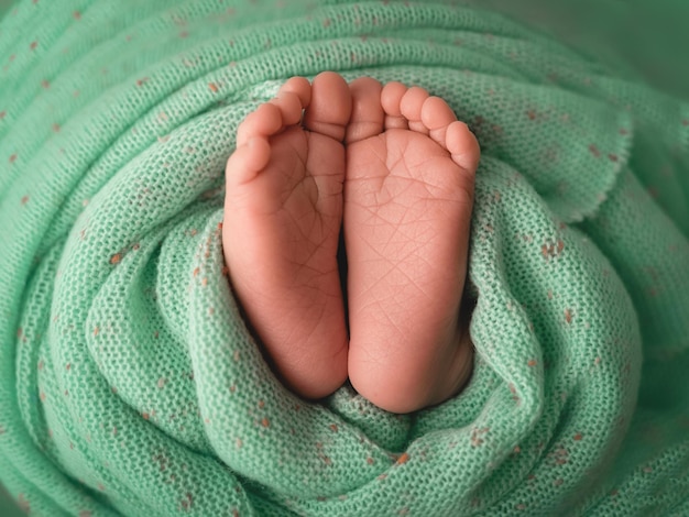 Foto pés de bebê no cobertor verde cuidados com o bebê nascimento nova vida conceito de família feliz