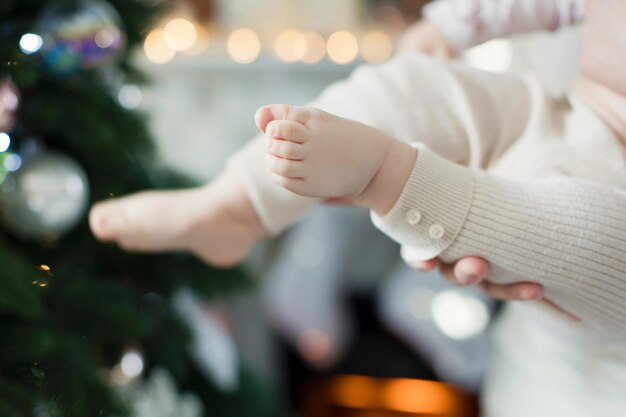 Pés de bebê perto das luzes da árvore de Natal