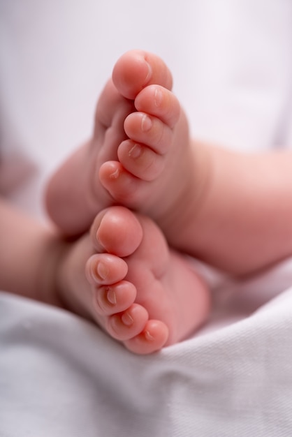 Pés de bebê recém-nascido em um cobertor branco, pés de menino,