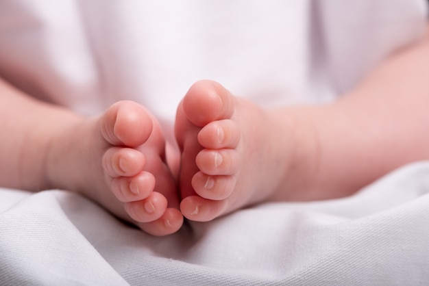 Pés de bebê recém-nascido em um cobertor branco, pés de menino,