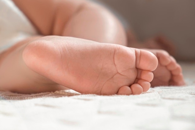 Pés de bebês minúsculos em cobertor de malha branca Close-up de pequeno pé nu de bebê dormindo na cama macia Dedinhos de bebê recém-nascido fofo Conceito de infância Maternidade Saúde Sono Criança recém-nascida Cuidados com a pele