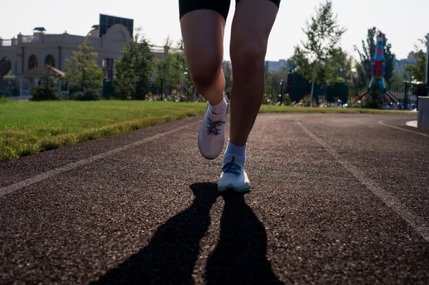 Pés de corredor correndo na estrada closeup em sapatos mulher fitness nascer do sol jogging treino bem-estar