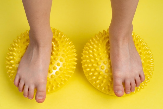 Pés de criança com balanceador amarelo sobre fundo amarelo claro tratamento e prevenção da deformidade em valgo do pé chato