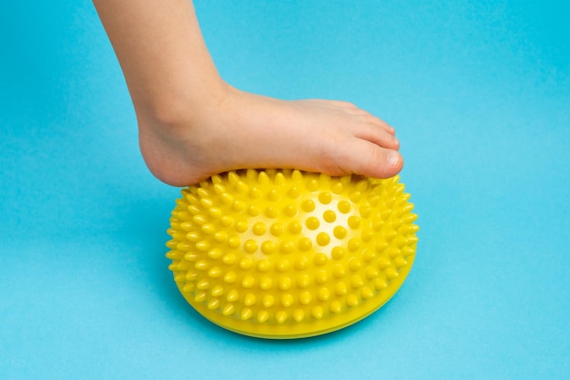 Pés de criança com um balanceador amarelo sobre fundo azul claro tratamento e prevenção de deformidade em valgo do pé chato
