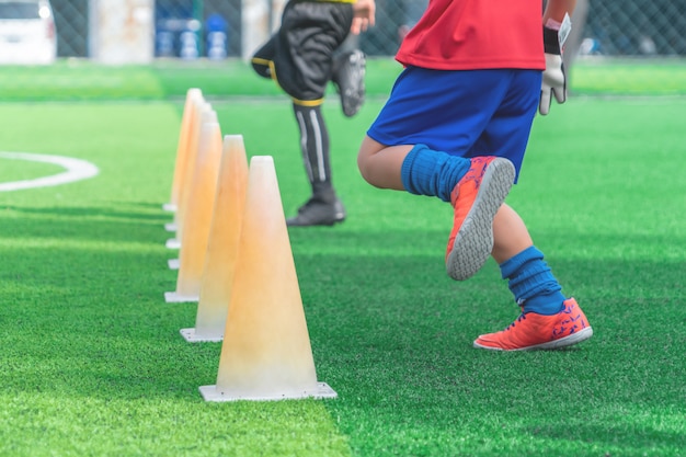 Pés de crianças com chuteiras no cone de treino