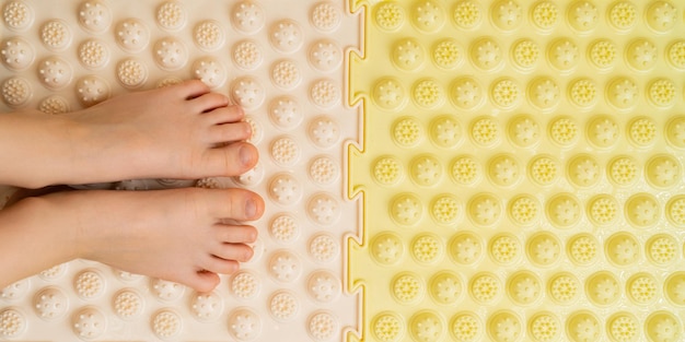 Foto pés de crianças no tratamento de tapete ortopédico bege e amarelo e prevenção de pés chatos hálux valgo para banner de texto