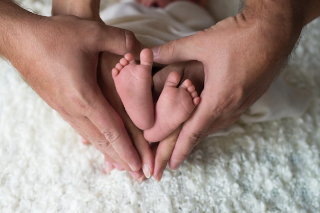 Pés de crianças pequenas nas mãos de papai e mamãe As pernas de um bebê recém-nascido