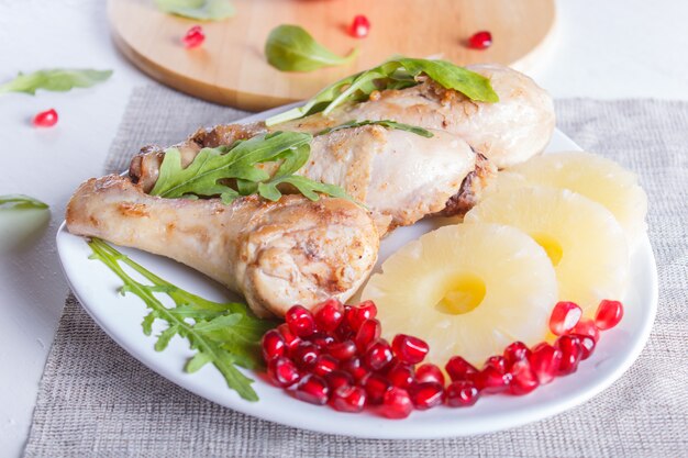 Pés de frango frito com as sementes do rucola, do abacaxi e da romã na superfície de madeira branca.